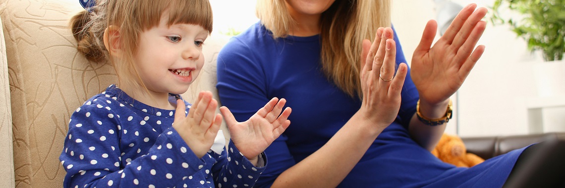 Ein Kind und eine erwachsene Person klatschen in die Hände - symbolisch für Therapiearbeit.