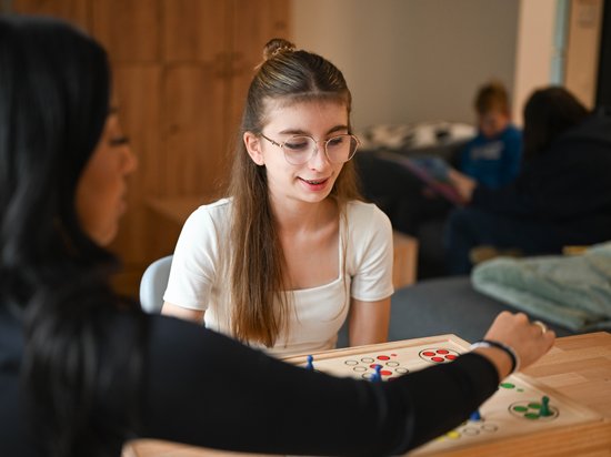 Mädchen spielt ein Spiel mit einer Betreuerin