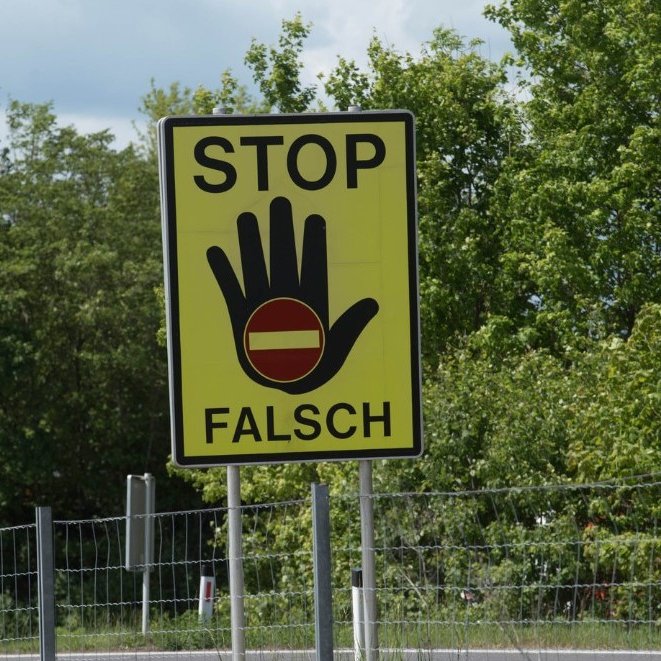 Verkehrsschild, auf dem eine Hand mit einem "Einfahrt-Verboten"-Symbol und den Worten "Stop Falsch" abgebildet ist. Bild: Canva