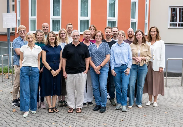 Eine Gruppe von Menschen posiert draußen für ein Foto.