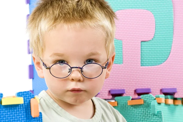 Kleiner Junge mit Brille zwischen Spielzeug