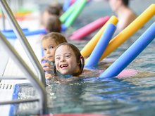 Lachende Kinder mit bunten Poolnudeln