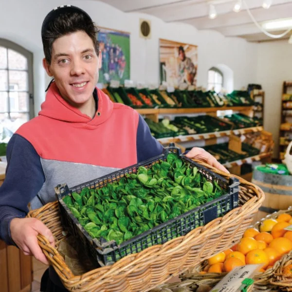 Mann hält Korb mit frischem Gemüse in einem Lebensmittelladen.