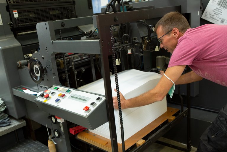 Christian Sas legt das Papier ganz exakt in die Maschine. Foto: Nicole Cronauge, Bistum Essen