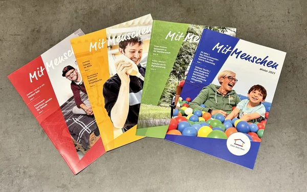 Vier verschiedenfarbige Ausgaben des Magazins MitMenschen.