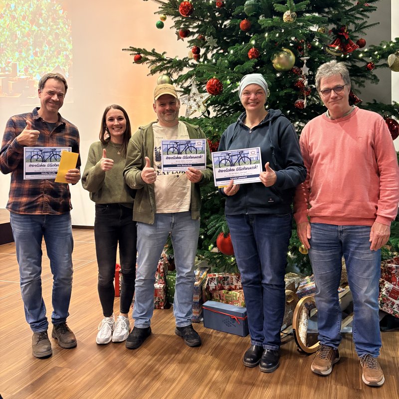 Fünf Personen posieren vor einem festlich geschmückten Weihnachtsbaum.