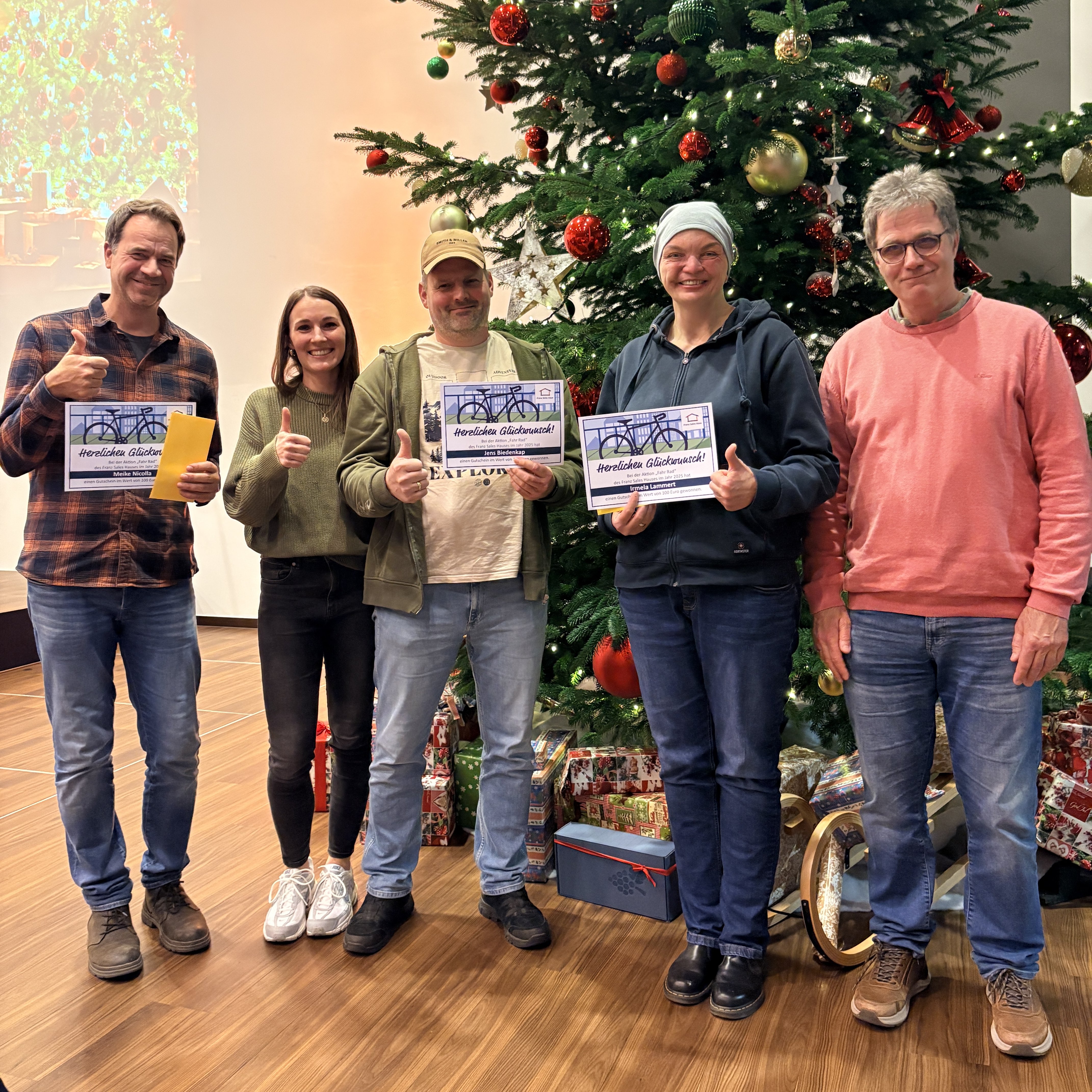 Fünf Personen posieren vor einem festlich geschmückten Weihnachtsbaum.