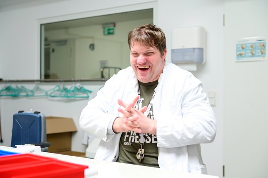 Beschäftigter im weißen Kitel arbeitet in einem Hygienebereich.