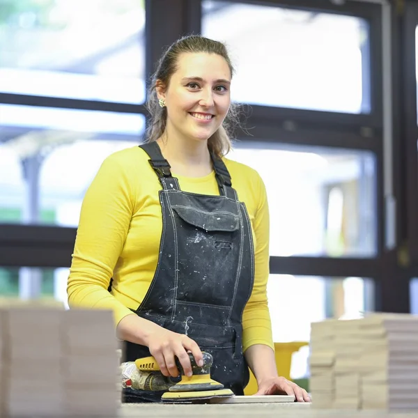 Beschäftigte schleift Einzelteile für die Schulmöbel-Produktion glatt.