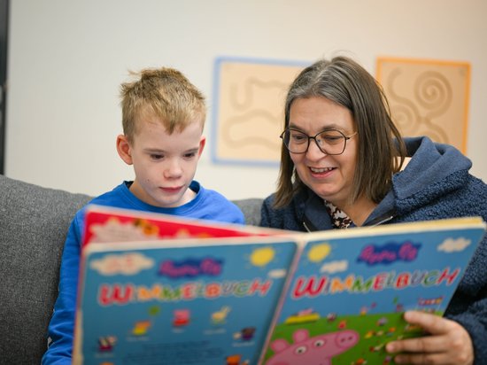 Kleiner Junge bekommt von Mitarbeiterin ein Buch vorgelesen