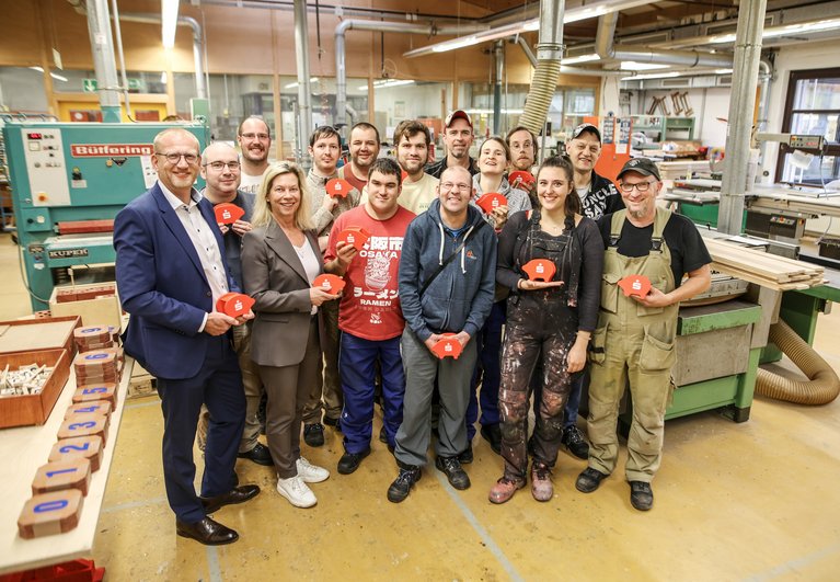 Sparkassen-Vorstand Oliver Bohnenkamp und Werkstatt-Geschäftsführerin Dr. Ann-Katrin Glüsing (1. Reihe v. links) freuen sich mit dem Team der Schreinerei über die gelungenen Holz-Sparschweine. Fotos: Sparkasse Essen/Sven Lorenz