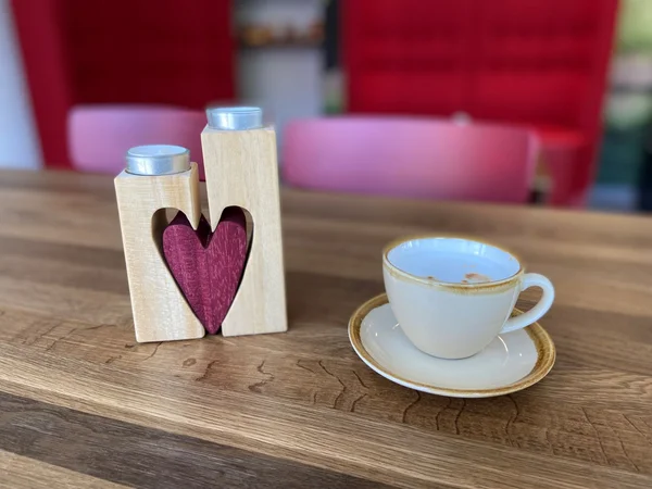 Tasse und Kerze in Herzform auf Holztisch.
