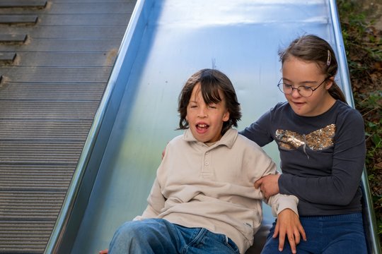 Zwei Kinder rutschen zusammen eine Rutsche hinunter, lachend und fröhlich.