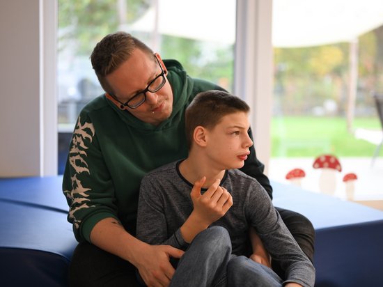 Kleiner Junge wird von einem Betreuer im Arm gehalten