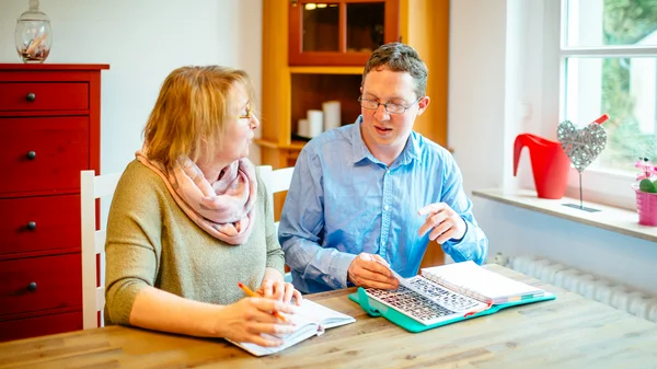 Zwei Personen sitzen an einem Tisch. Eine Frau berät einen jungen Mann.