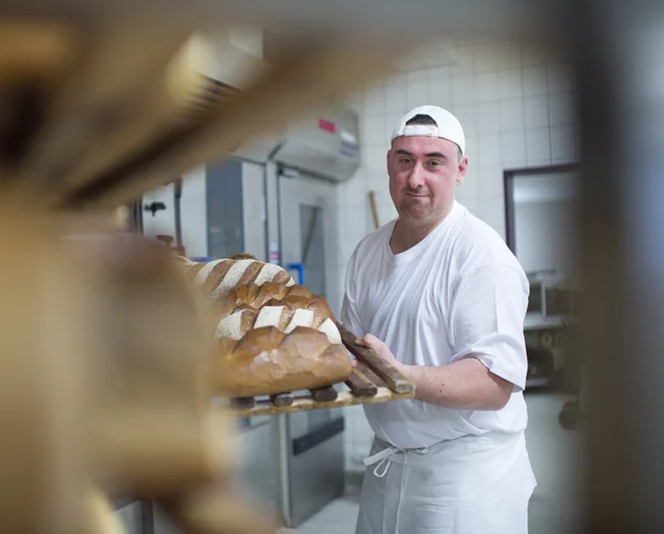 Bäcker in weißer Kleidung holt frisches Brot aus dem Ofen der Franz Sales Hausbäckerei.