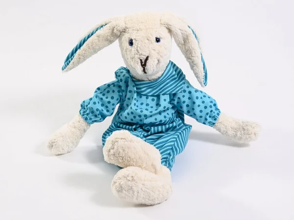 Stoffkaninchen in blauem Kleid mit Punkten und Streifen auf weißem Hintergrund.