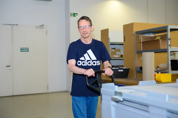 Beschäftigter arbeitet mit Hubwagen Ware auf Palette