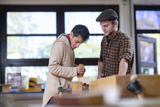 Fachkraft leitet Mensch mit Behinderung in der Schreinei an.