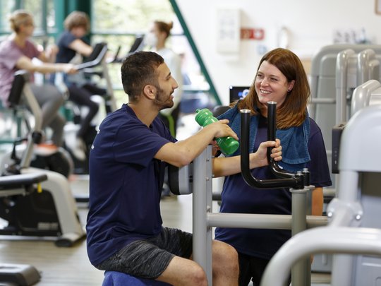 Klient und Betreuerin im Fitnessstudio.