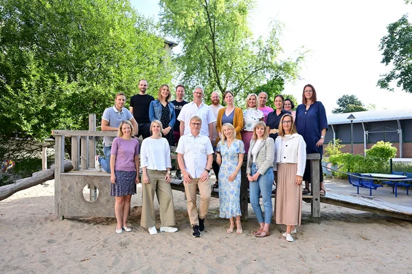 Eine Gruppe von Menschen posiert draußen für ein Foto.