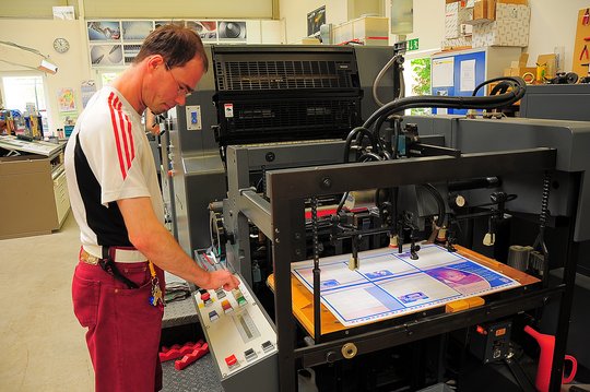 Beschäftigter arbeitet an einer Druckmaschine