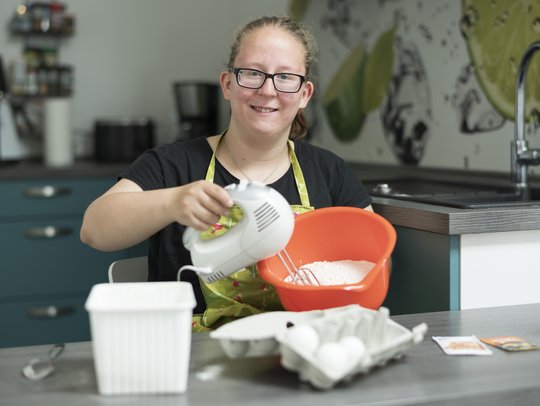Junge Frau bäckt in ihrer Küche einen Kuchen.