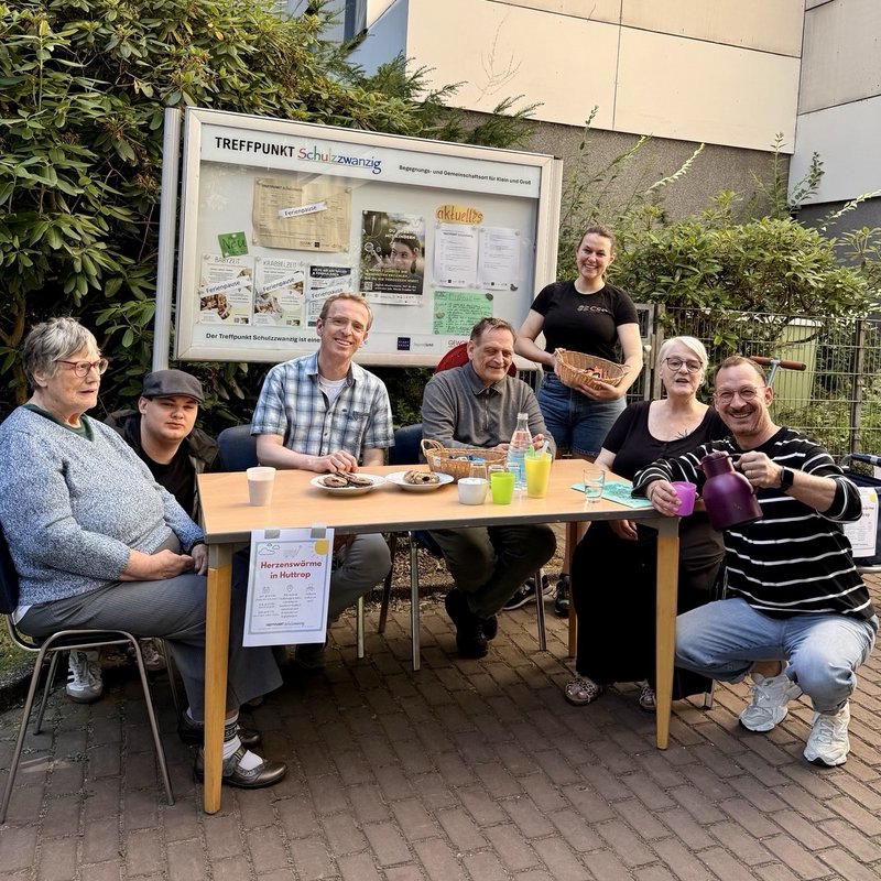 Die Akteure des Projekts Herzenswärme an einem Tisch mit Getränken uns Snacks