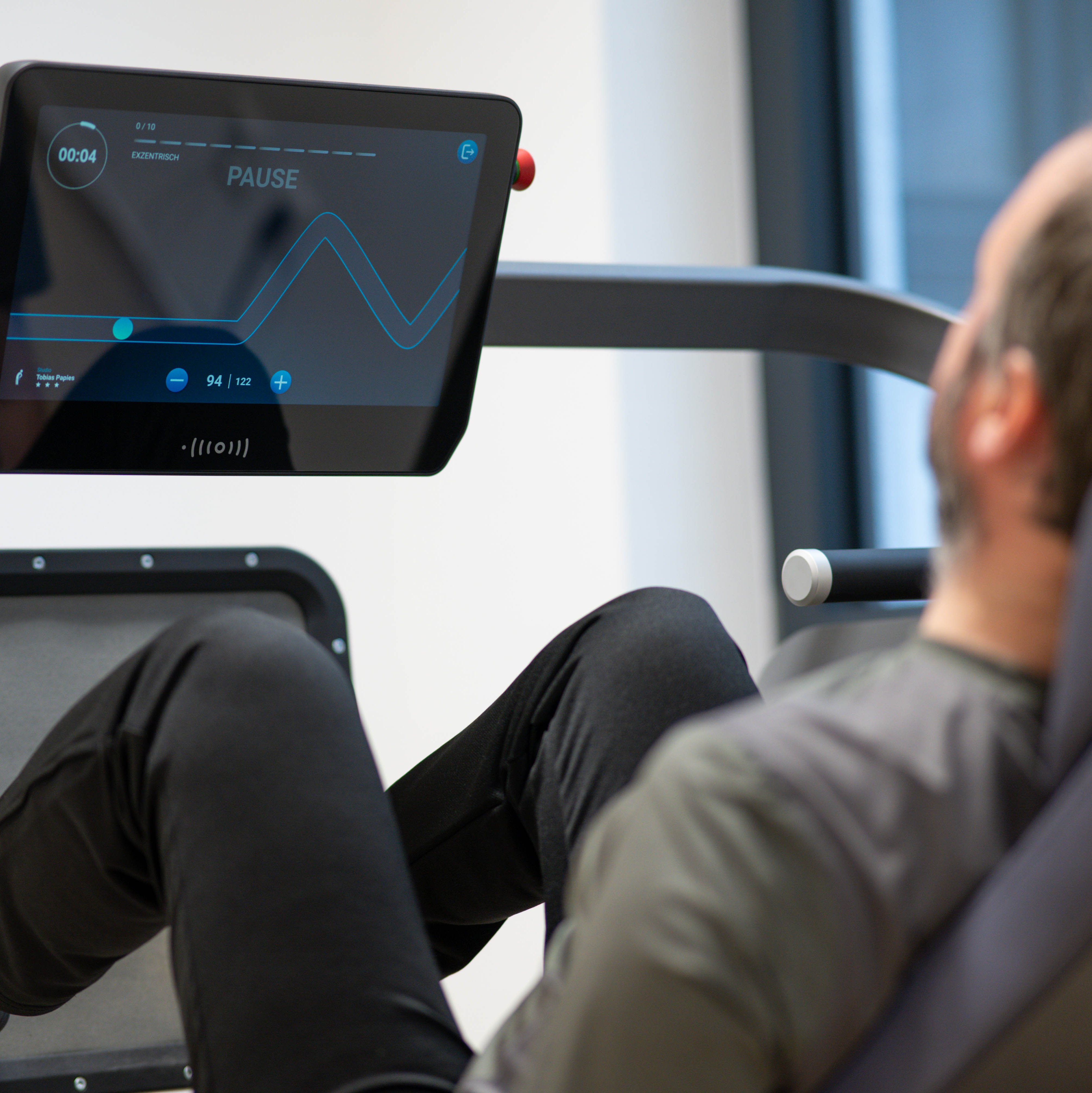 Ein Fitnessgerät mit Bildschirm, an dem ein Mann trainiert.
