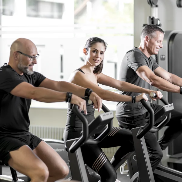 Menschen unterschiedlichen Alters trainieren auf Milon-Geräten im Fitnessstudio.