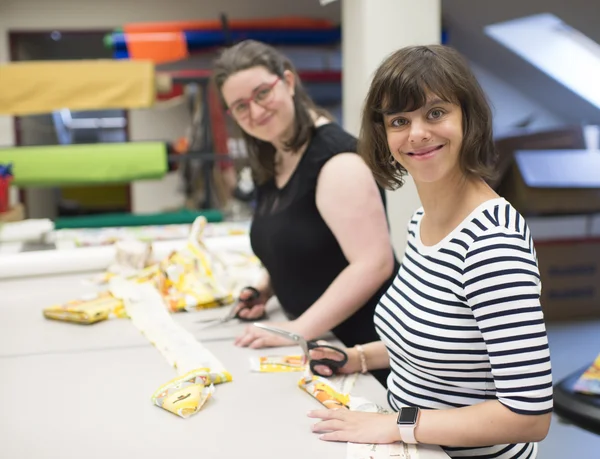 Zwei Personen basteln lächelnd an einem Tisch.