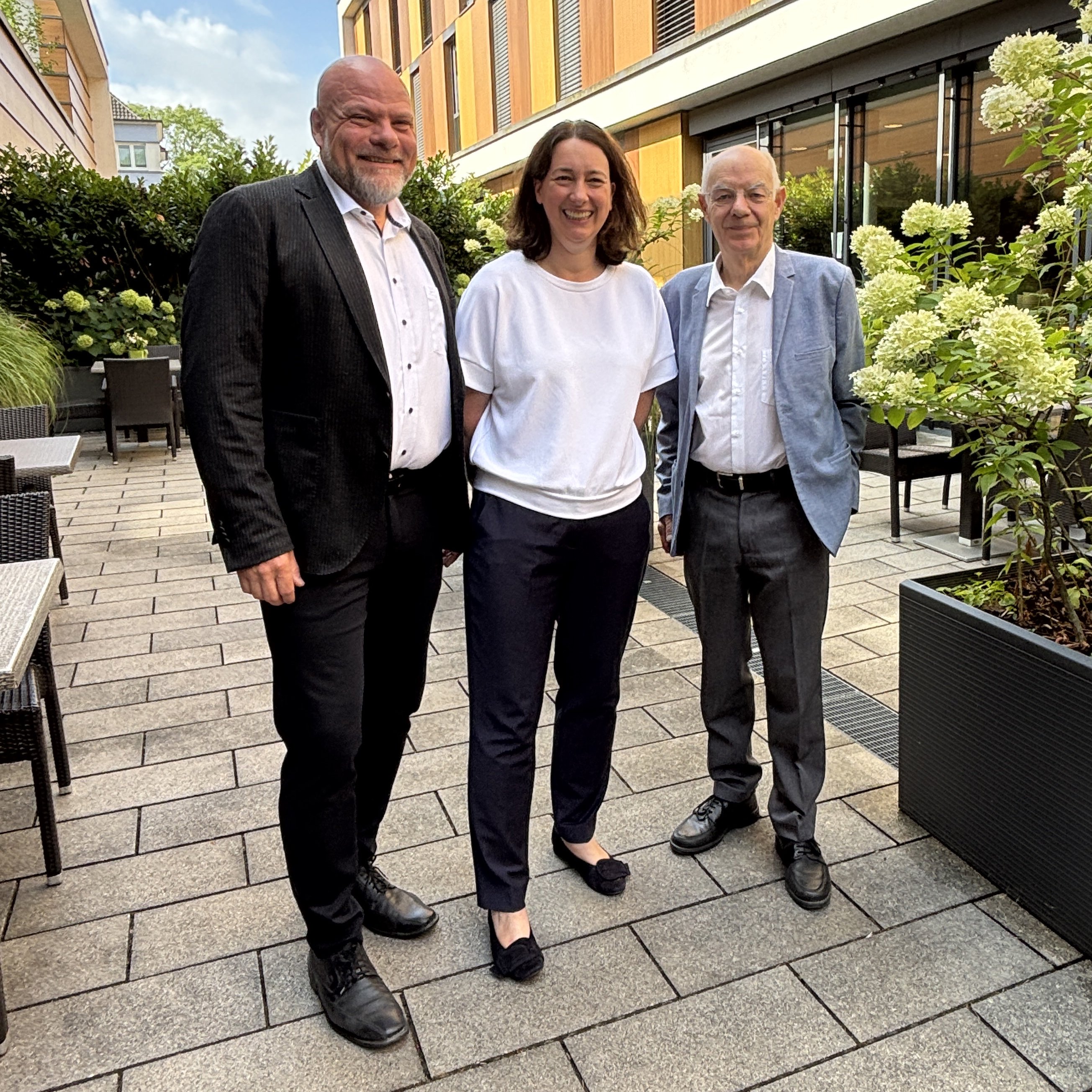 Der Vorstandsvorsitzende Holger Gierth, die neue Vorständin Daniela Schneider und der Kuratoriumsvorsitzende Prof. Nehen stehen nebeneinander auf der Terrasse vom Hotel Franz