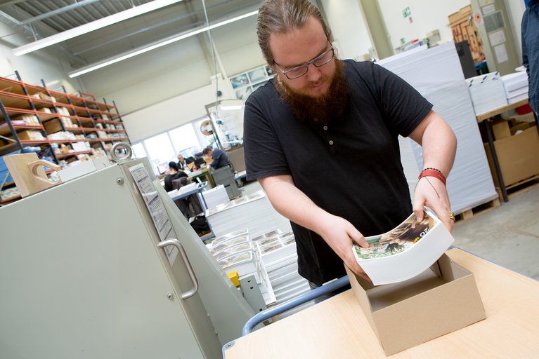 Benjamin Frieß verpackt die fertigen Info-Zettel.