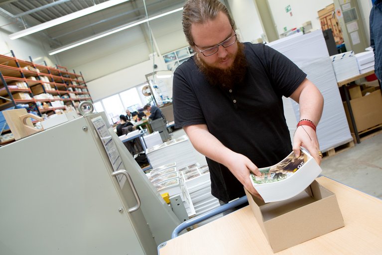 Benjamin Frieß verpackt die fertigen Handzettel. Foto: Nicole Cronauge, Bistum Essen