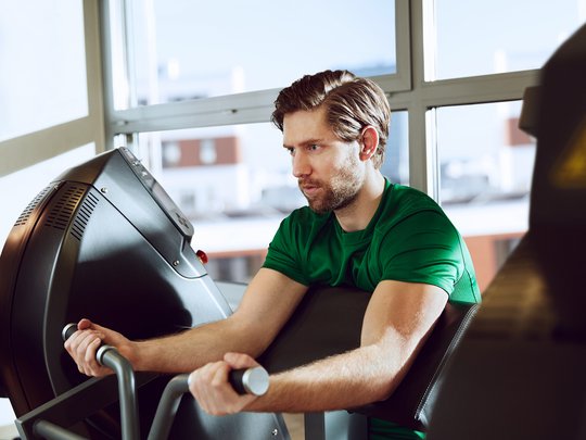 Junger Mann trainiert an Fitnessgerät