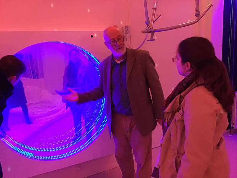 Personen betrachten eine farbige Lichtinstallation in einem Raum.