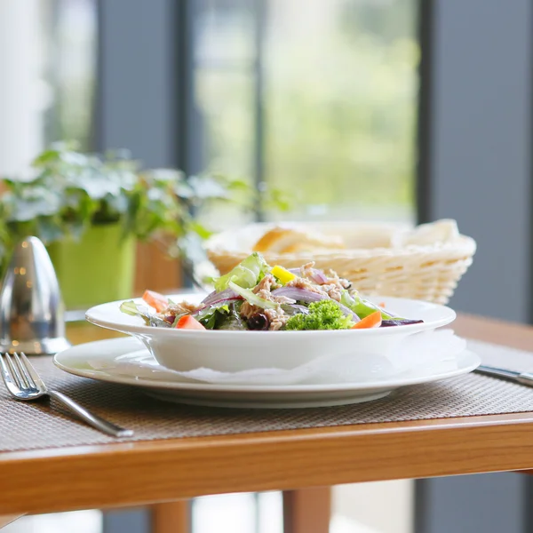 Ein gedeckter Tisch mit Salat, Brot, Besteck