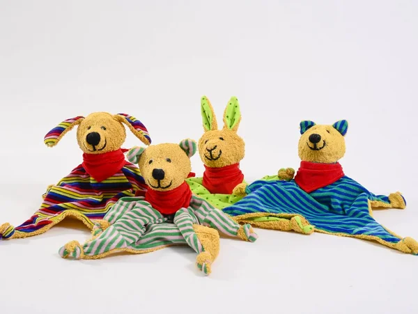 Vier bunte Kuscheltiere mit roten Halstüchern auf weißem Hintergrund.