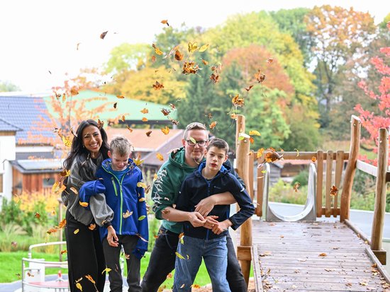 Kinder und Betreuer spielen mit Herbstlaub