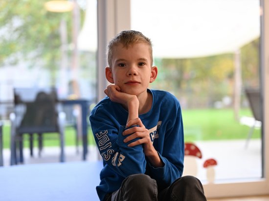 Ein kleiner Junge ist zur Ruhe gekommen und betrachtet nachdenklich das Spiel der anderen Kinder.