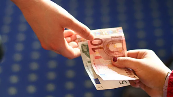 Eine Hand reicht der anderen Geldscheine.