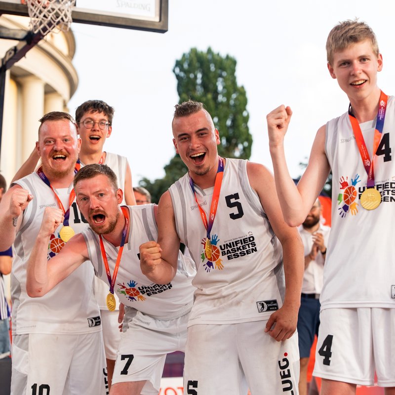 Fünf Basketball-Spieler jubeln in die Kamera. Sie haben Goldmedaillen um den Hals.
