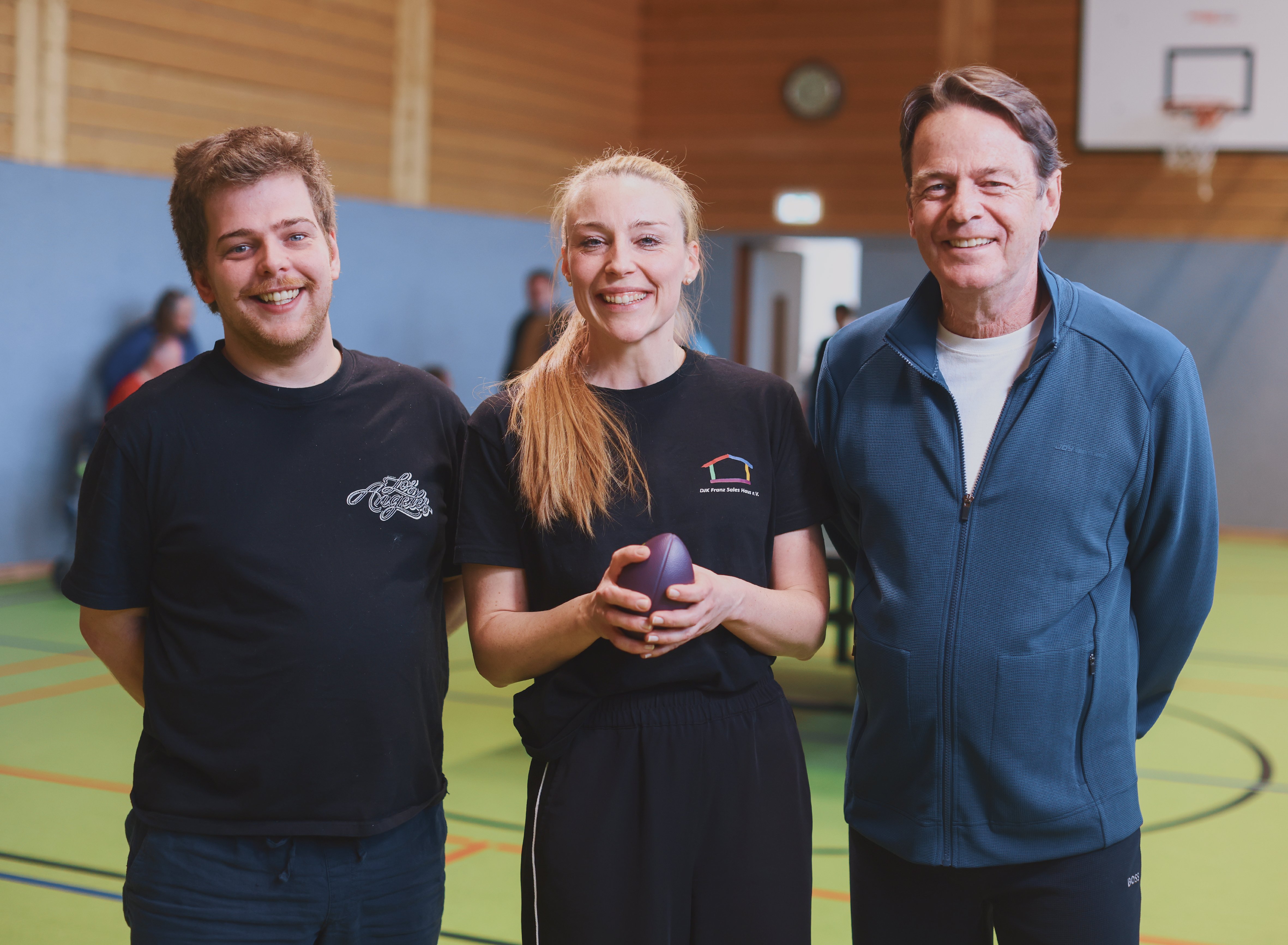 Teilnehmer Dennis, Leiterin Julia Hollensett und Rudi Cerne stehen nebeneinander und blicken in die Kamera.