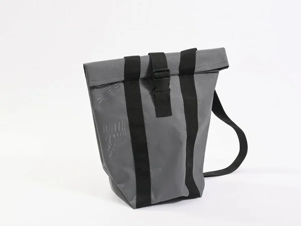 Graue Tasche mit zwei schwarzen Riemen und einem Tragegurt auf weißem Hintergrund.