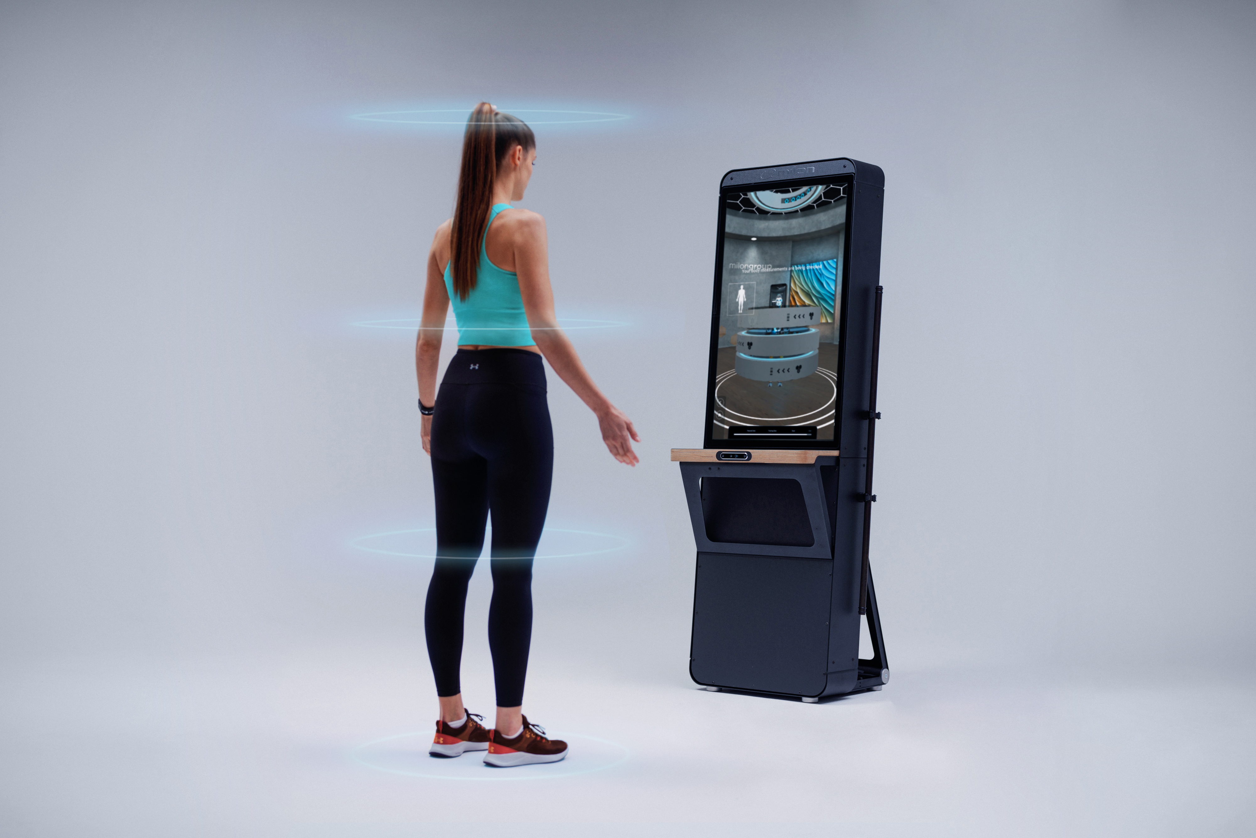Frau in Sportbekleidung steht vor dem Bodyscanner, der ihr Fitnesslevel ermittelt.
