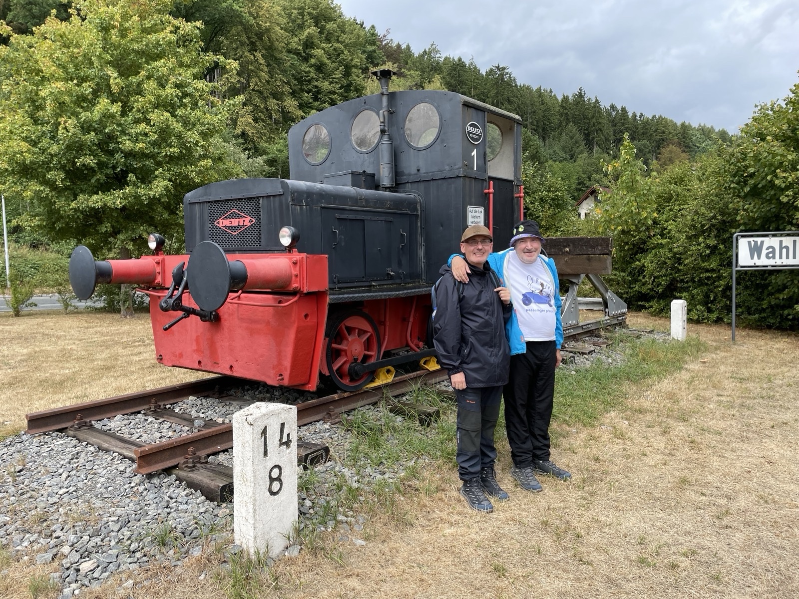 Zwei Pilger vor einer Lok im Wald