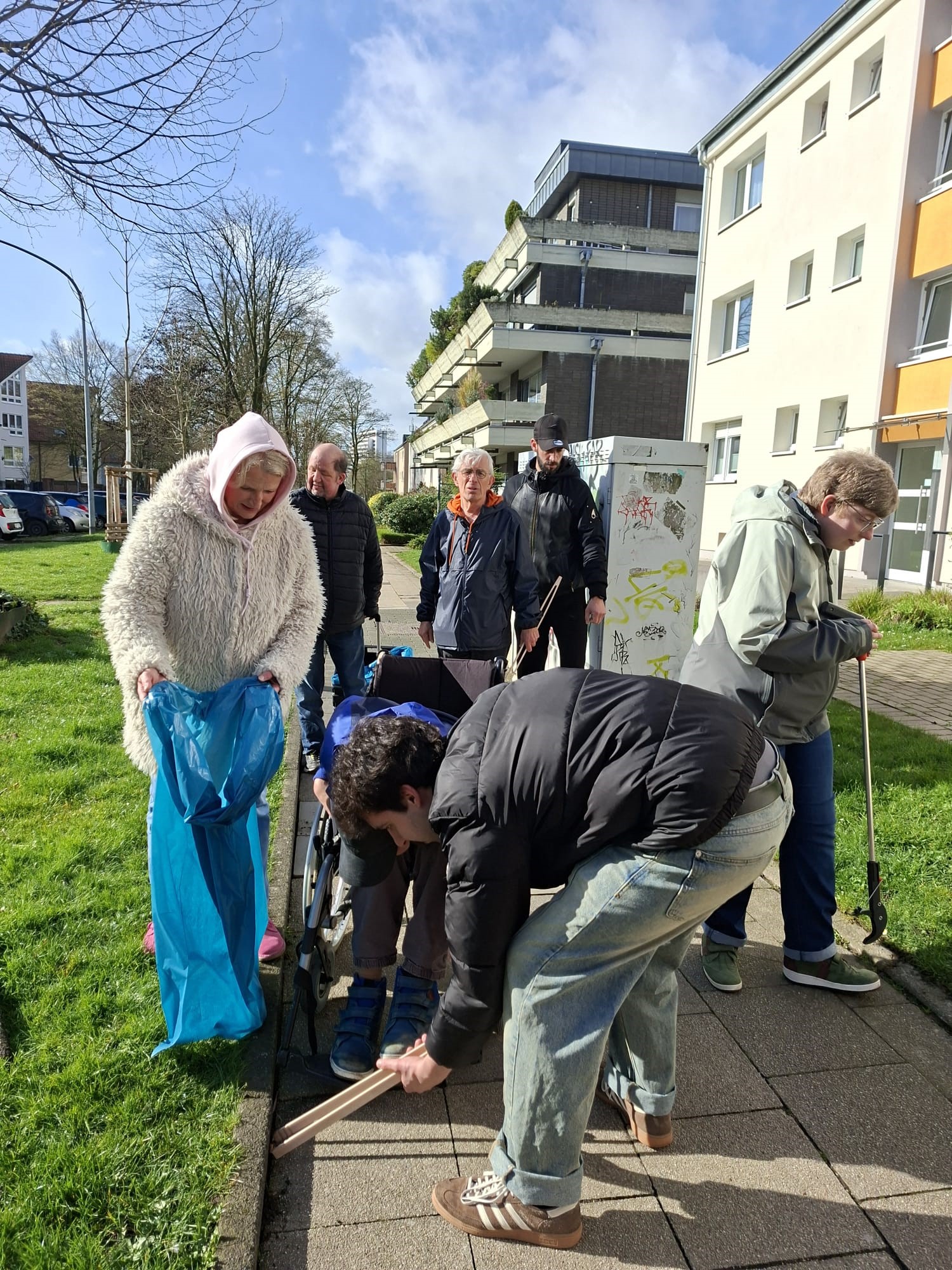 In einer Wohnsiedlung sammelt die Seniorengruppe der Tagesstruktur Müll vom Bürgersteig.